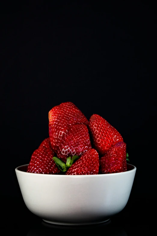 a white bowl with strawberries on top