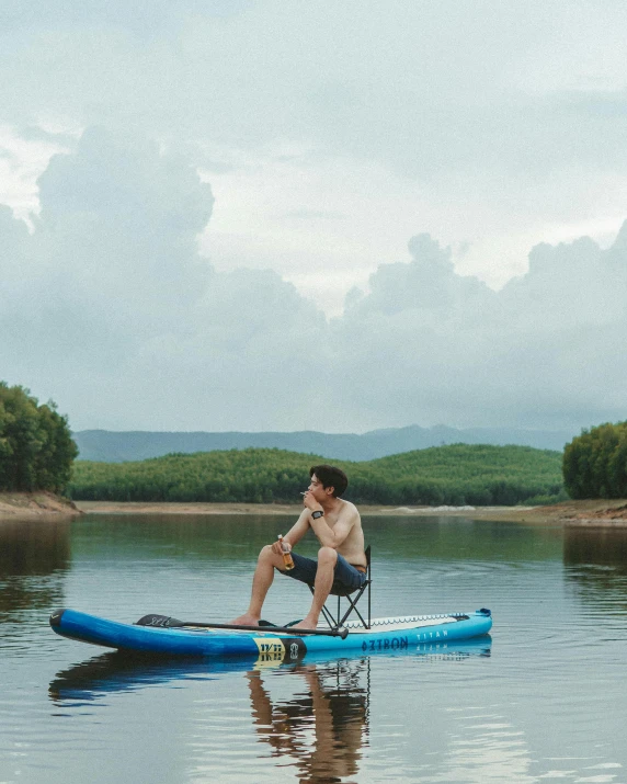 a man sitting on top of a blue boat on top of a body of water