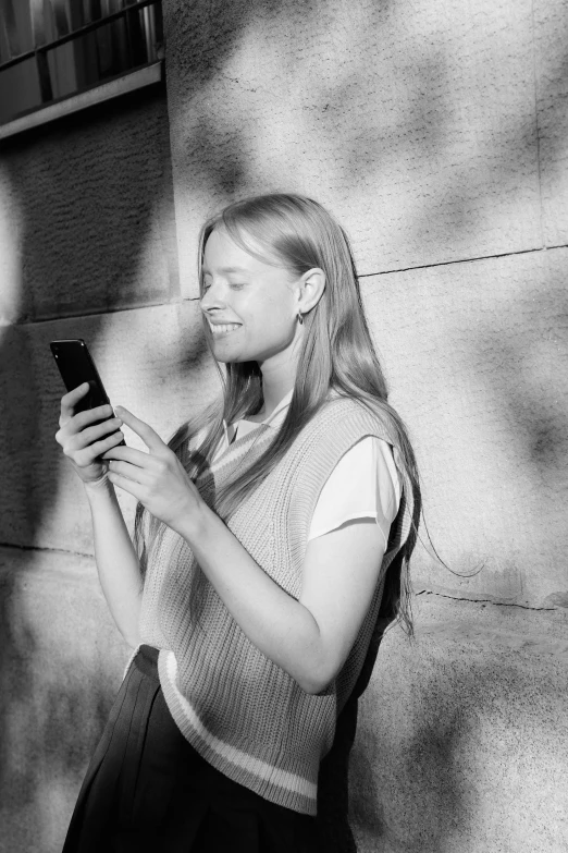 a girl wearing a vest checks her cell phone