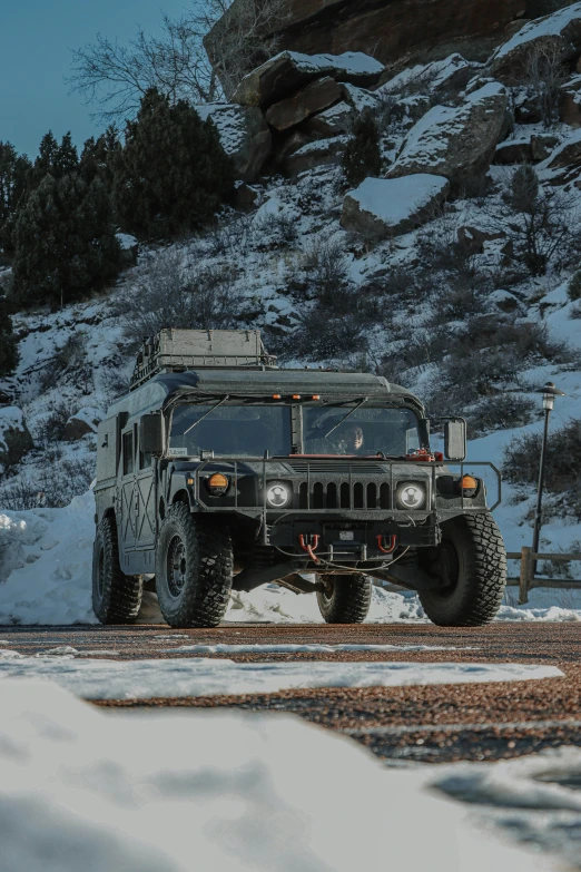 two military trucks driving in a snowy parking lot