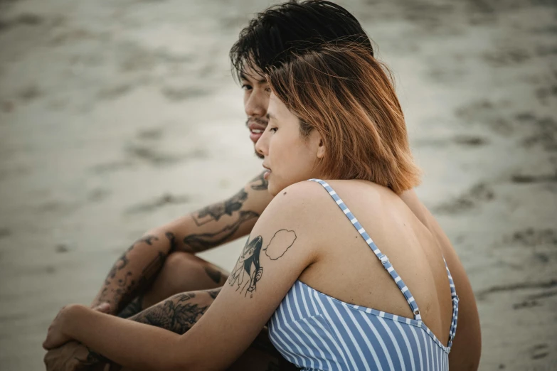 a person with tattoos sitting in the sand