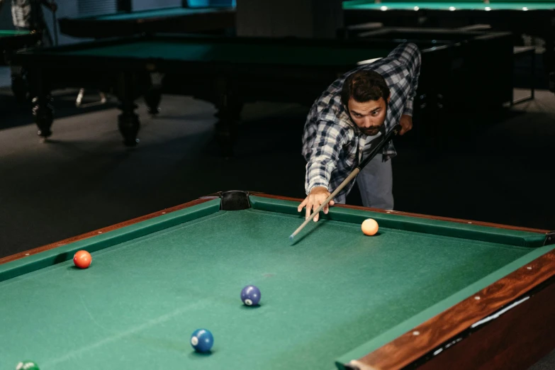 a man in plaid shirt playing pool