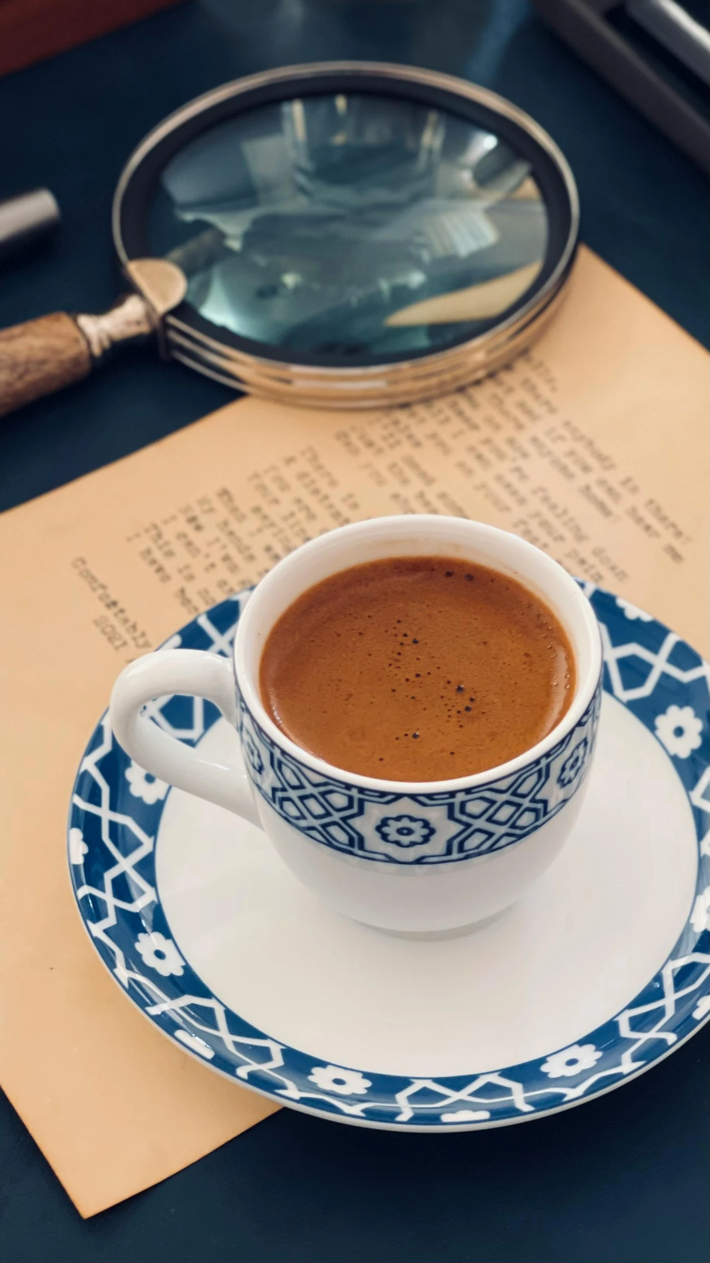 the cup of coffee is in front of a magnifying glass