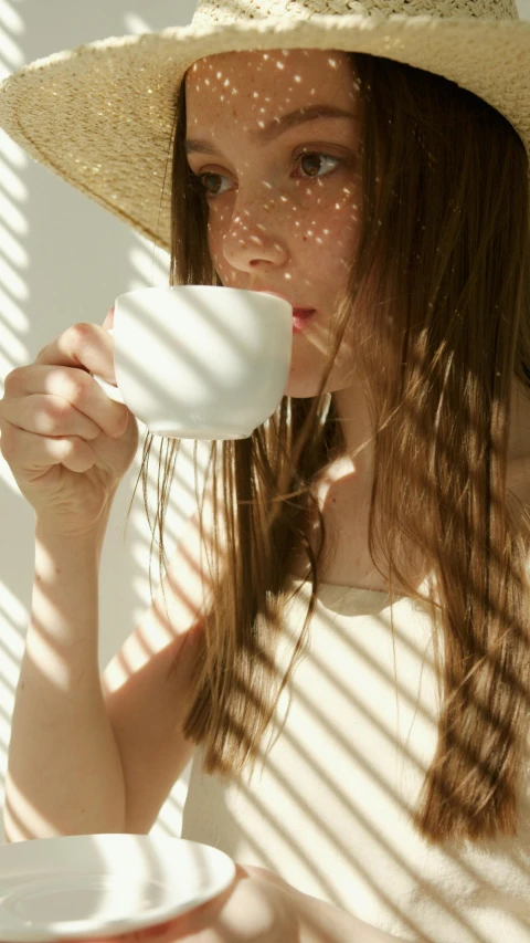 a girl is holding a coffee cup and looking into the camera