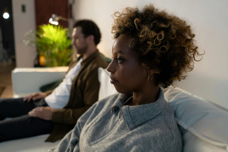 two men sitting on couches watching soing while a woman is on the floor in the background