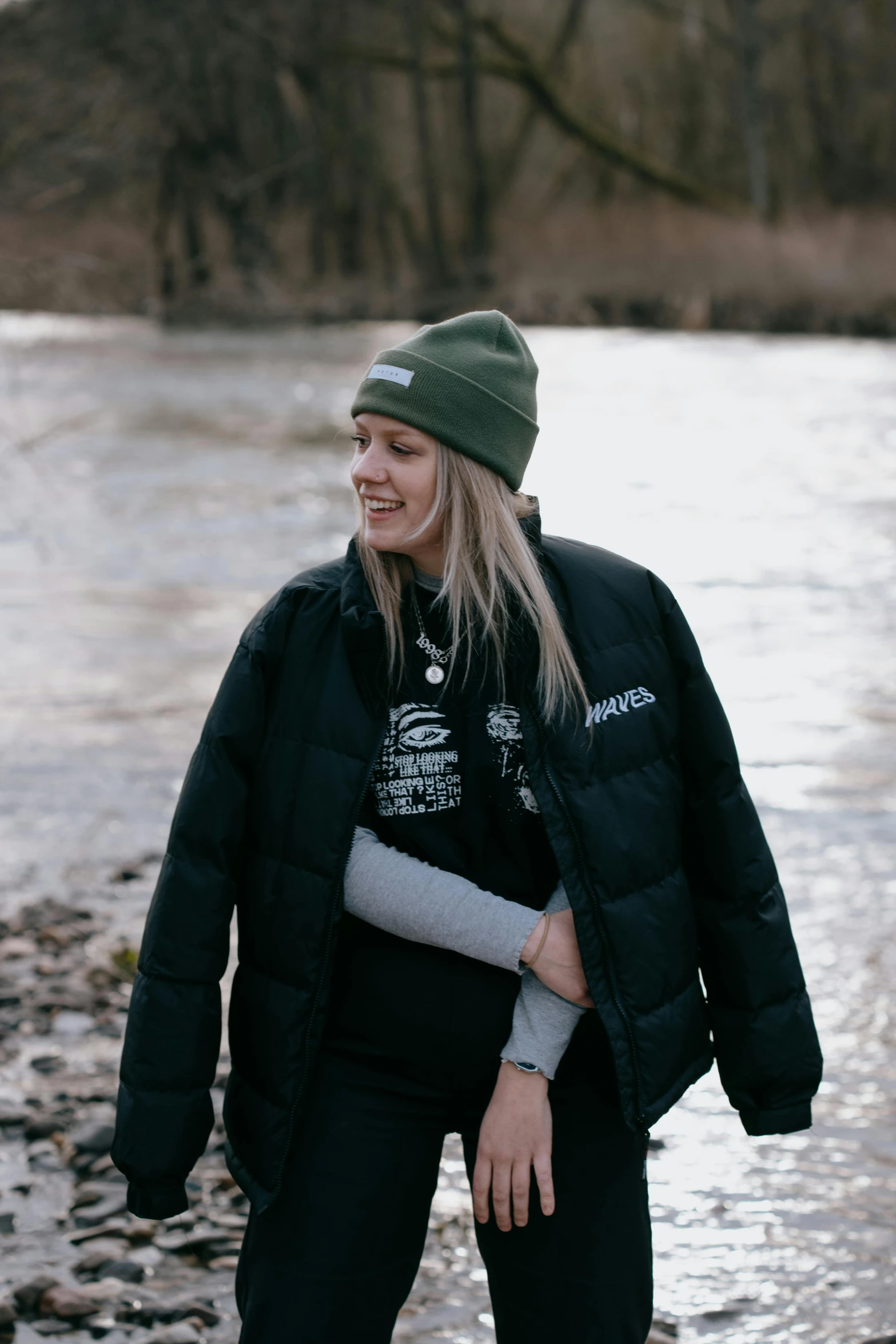 a woman smiling next to the water in winter