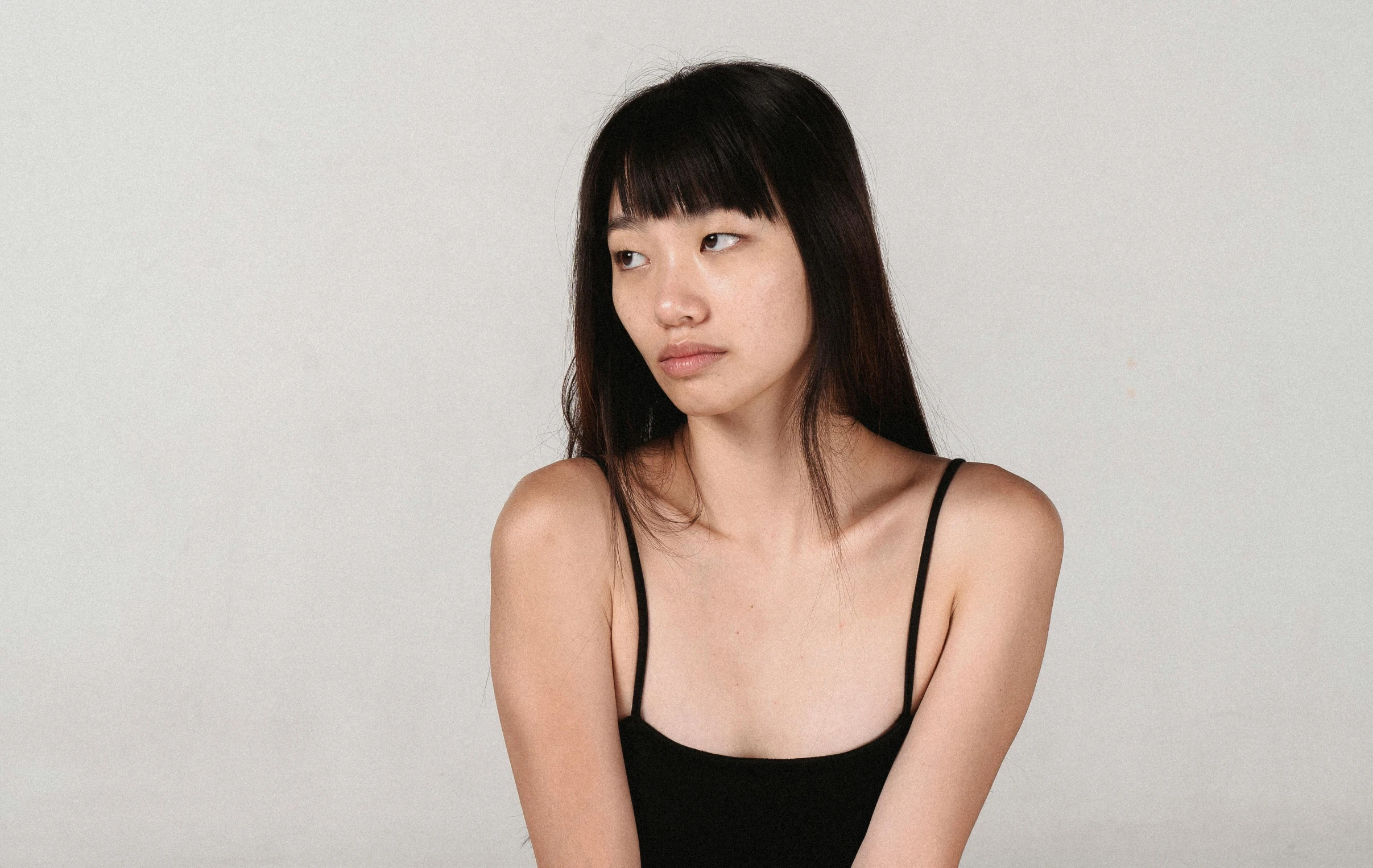 a woman is sitting on a stool against a wall