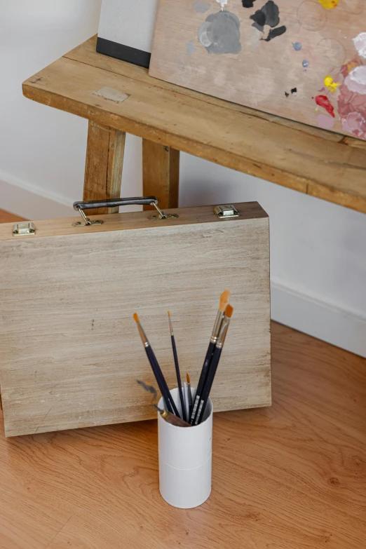 an easel and pencils in a box on a hard wood floor