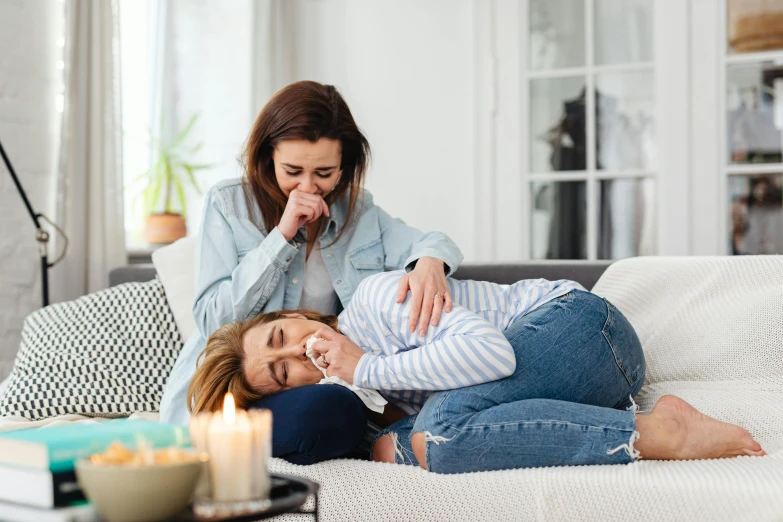 a mother and daughter laying on the couch