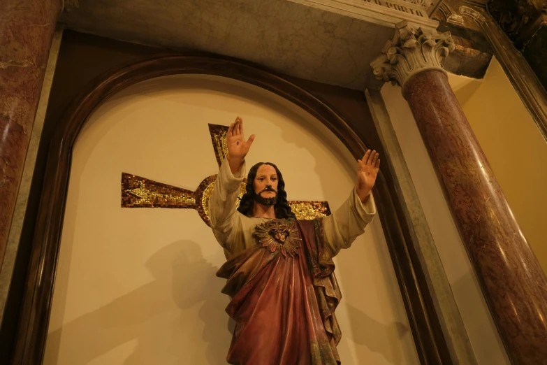 a statue of jesus in a church holding his arms out