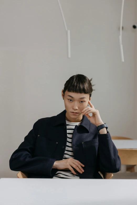 a young man sitting at a table talking on a cell phone