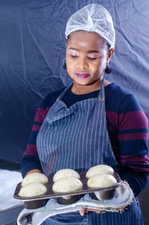 a woman is holding a tray full of donuts