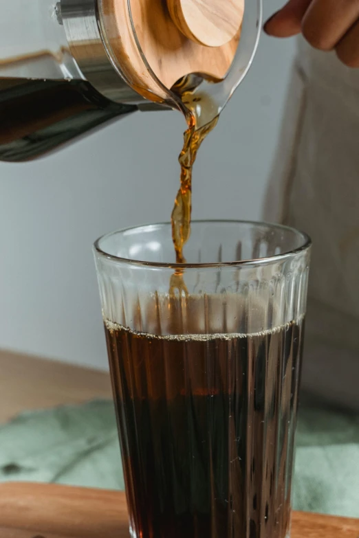 someone pouring liquid into a glass filled with some food