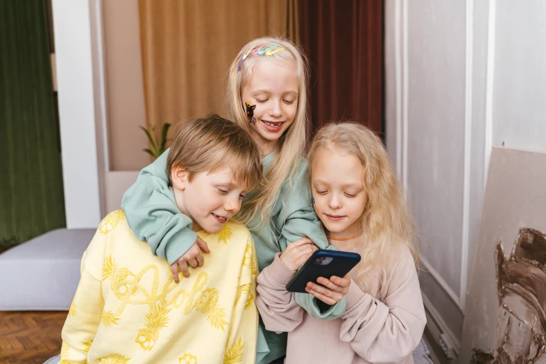 two s look at a tablet screen while sitting in a chair with another girl and boy