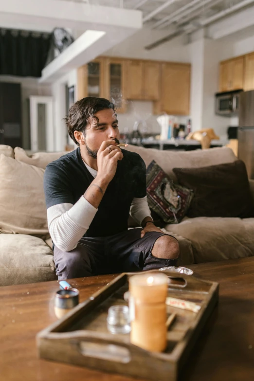 the man sits on the floor in front of a tray of drinks