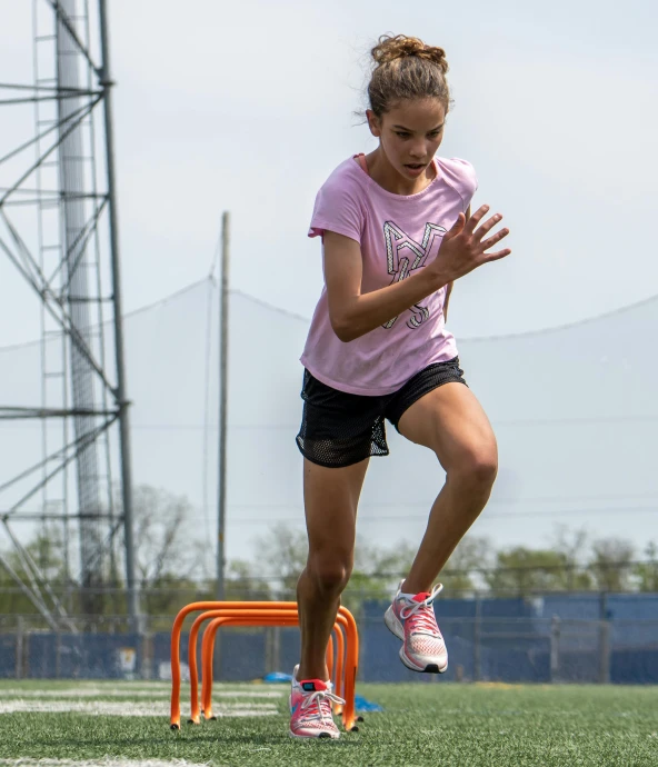 a female in a pink shirt is jumping to catch a frisbee