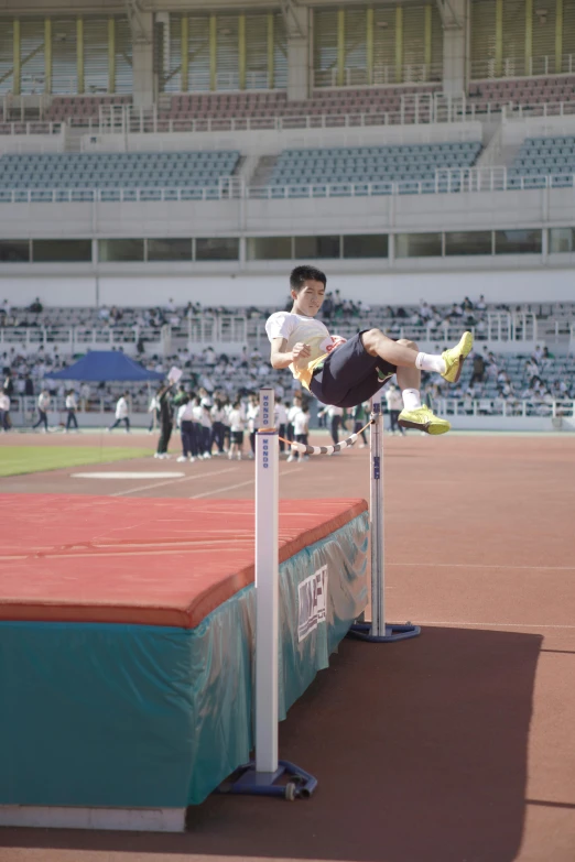 a man jumps over an obstacle in front of an audience