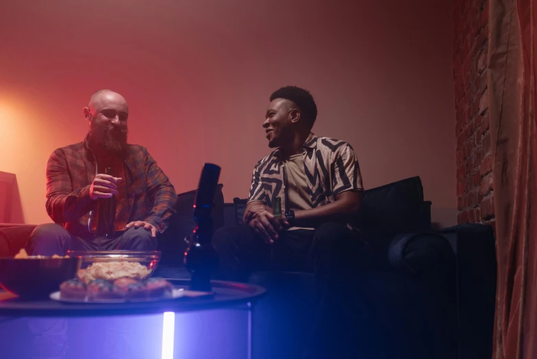 two men are seated in front of television at night