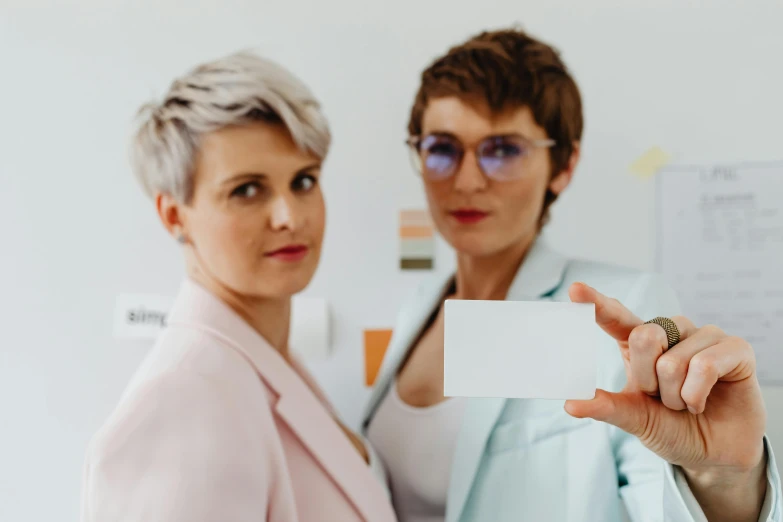 a woman is holding up a business card with another person