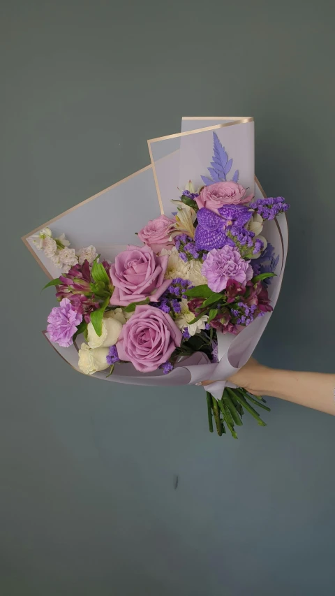 purple and white flowers in a bouquet being held by a person