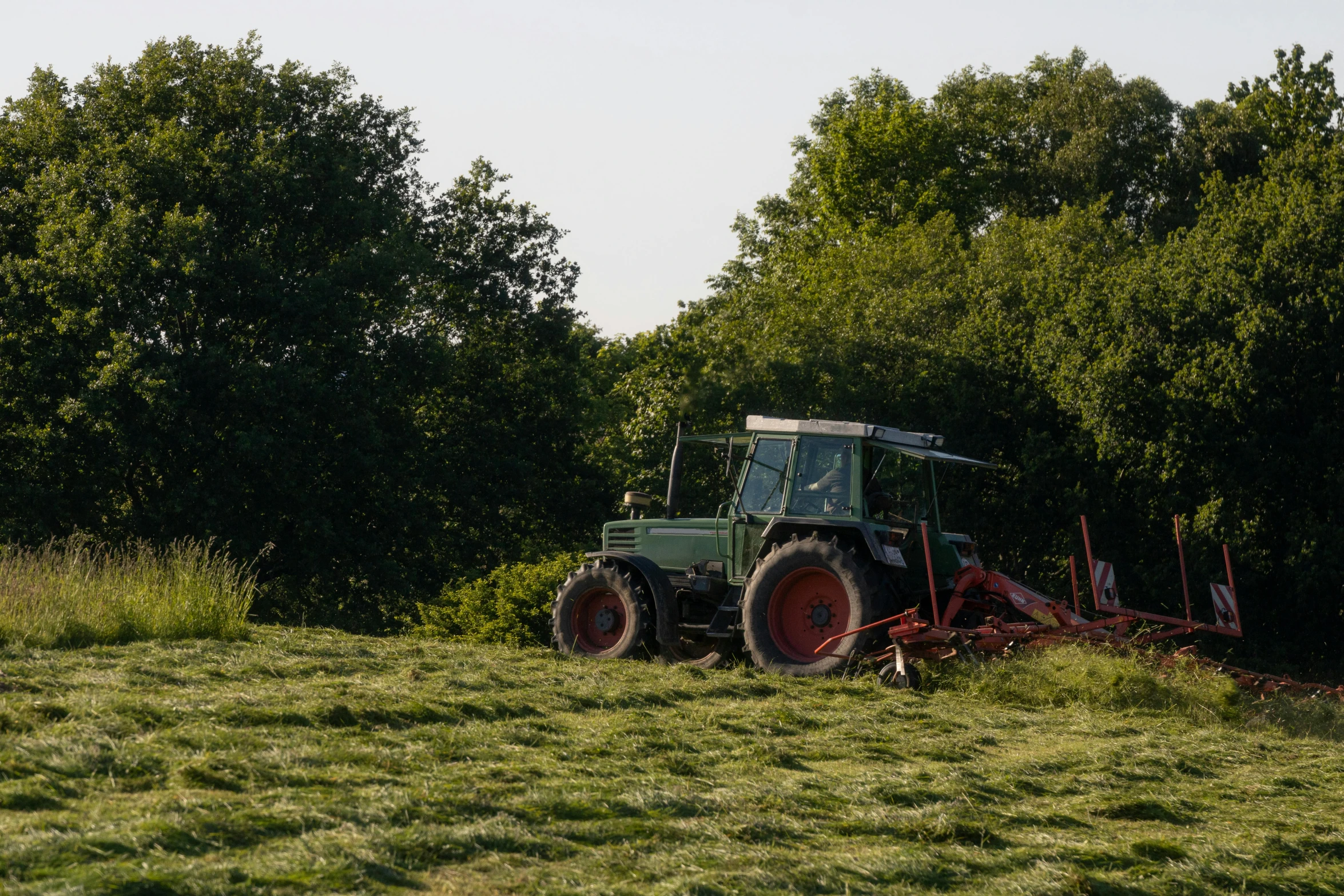 a tractor with a mower attached is parked in a field of grass