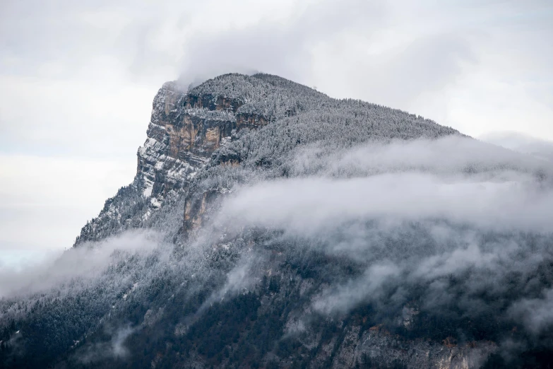 the top of the mountain has a few small clouds around it