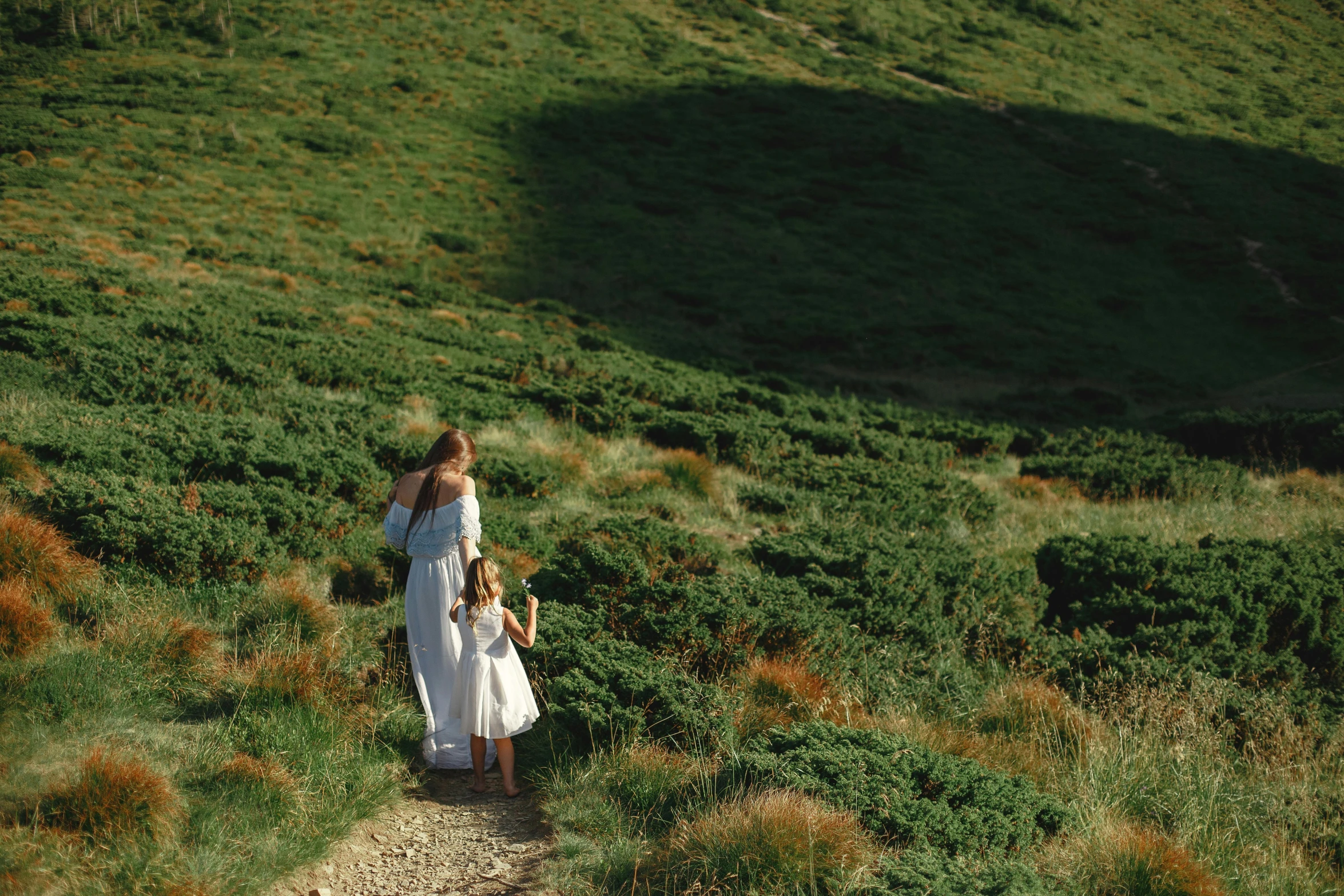 there are two women that are walking down the trail