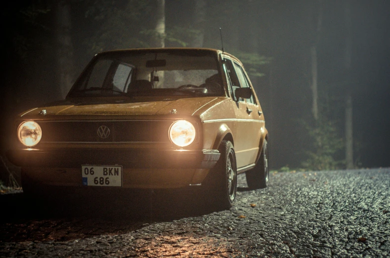 a yellow car driving through the woods in the rain