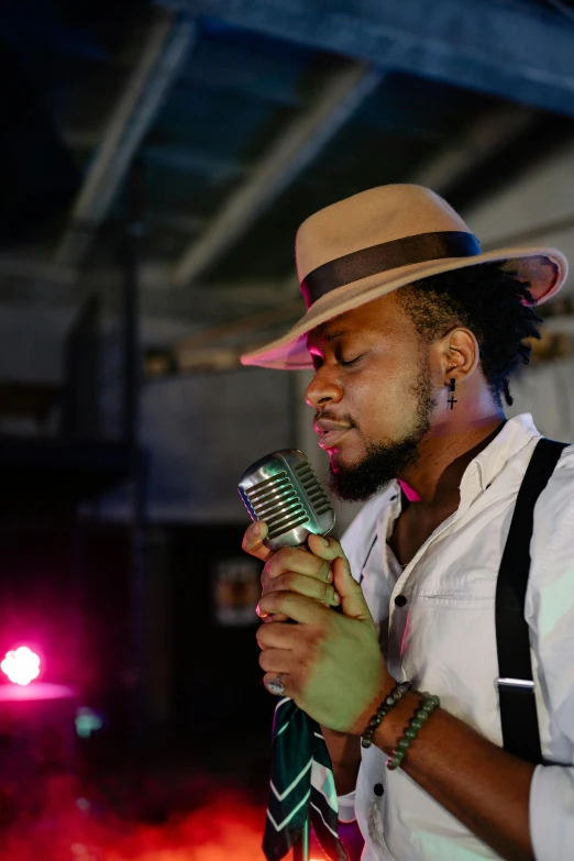 a man with a fedora holding a microphone