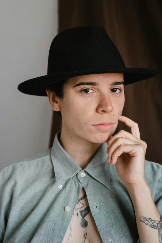 a person with tattoos on their arm wearing a black hat