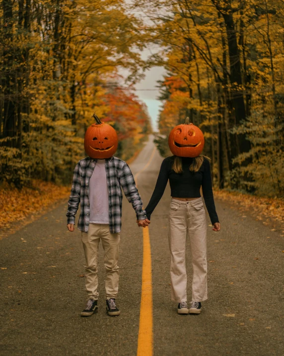 two young people walking down a road with jack and sally pumpkin helmets on their heads