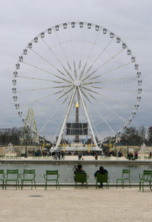 a ferris wheel on the beach in front of two park benches