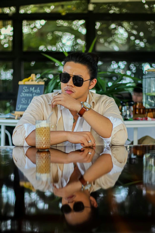 a man with sunglasses sits at a table and looks off to the side