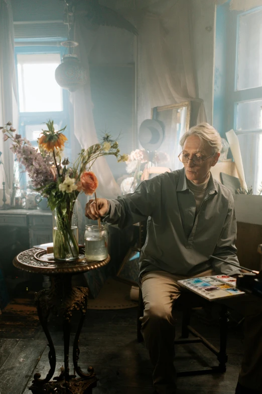 a man sits on a chair with a flower vase and magazine on the table
