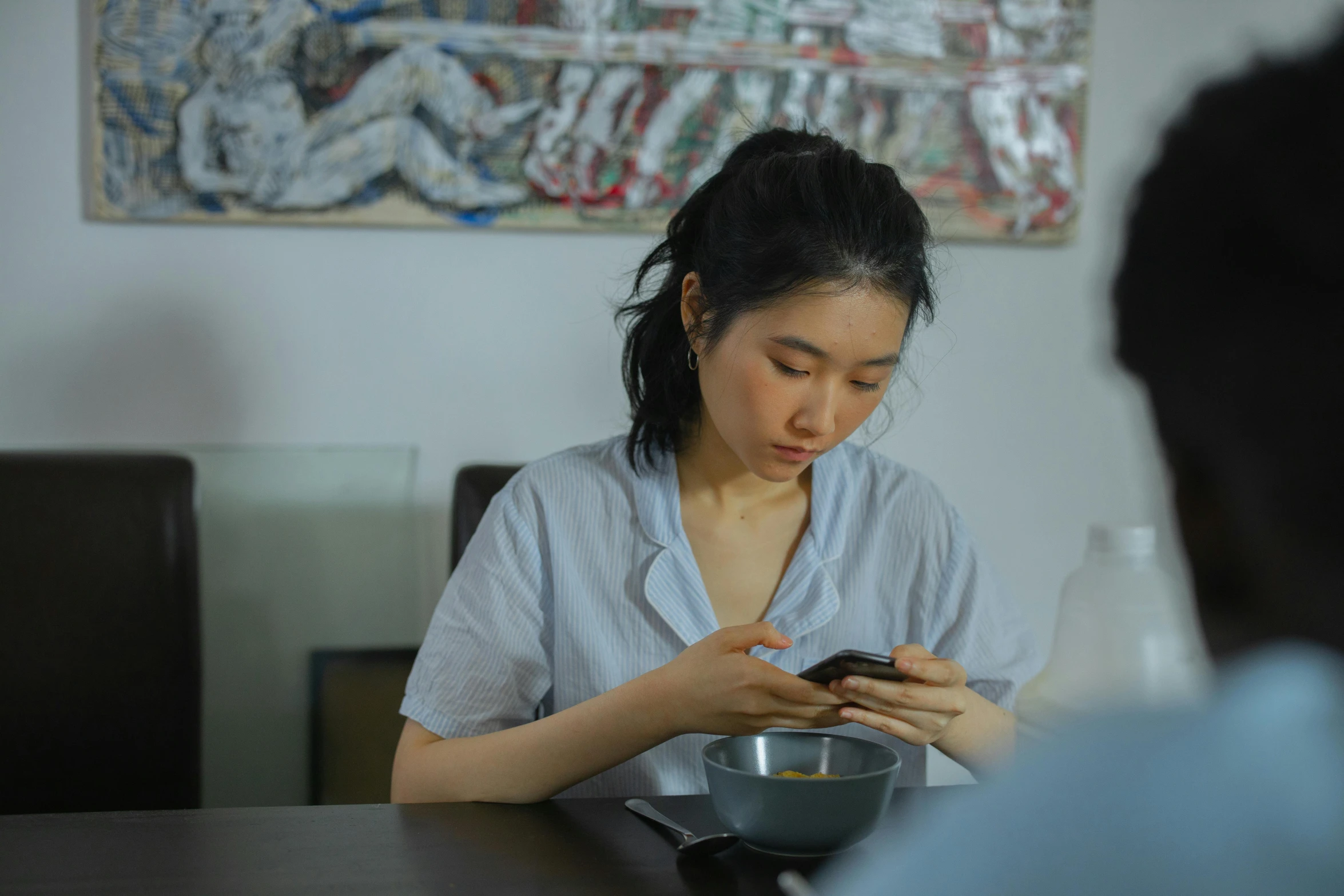 a woman sitting at a table while using a cell phone