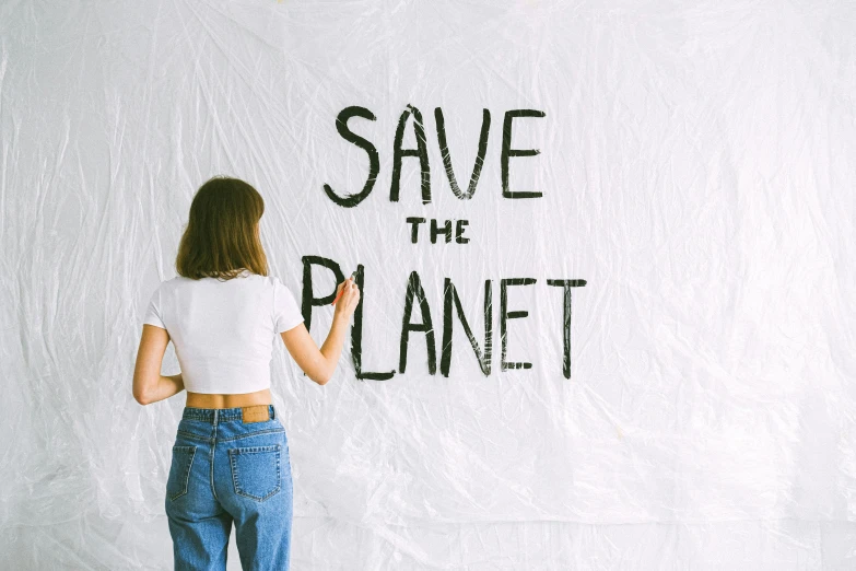 a person writing save the planet on a white wall