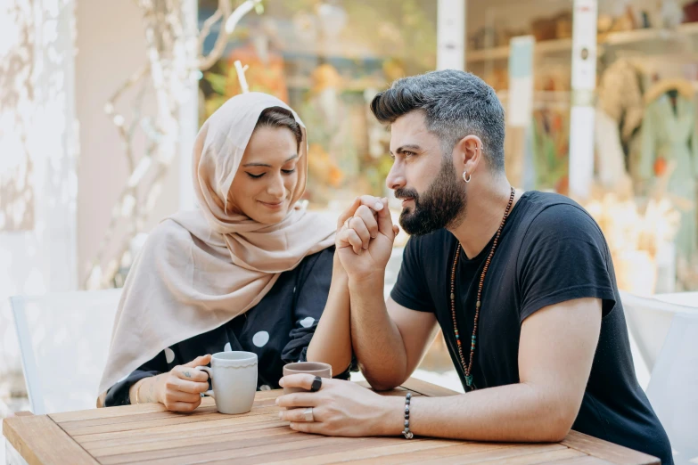 a young man and woman at an outdoor table in a courtyard