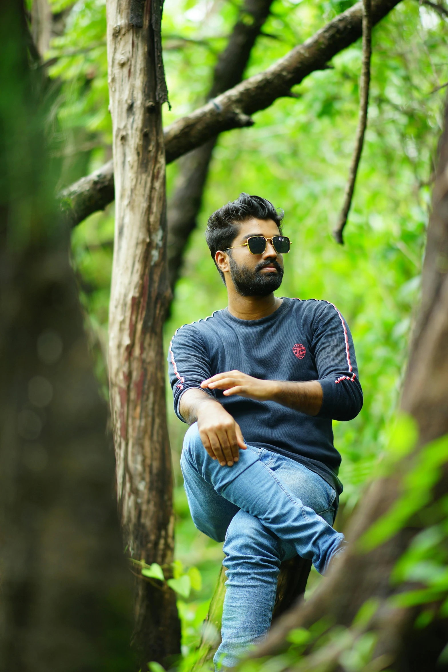 a man is sitting on a tree while wearing shades