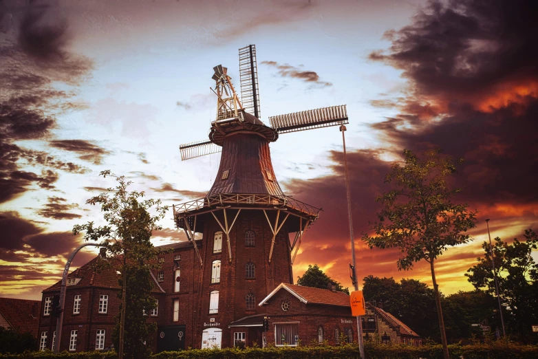 a view of an old windmill in front of a colorful sky