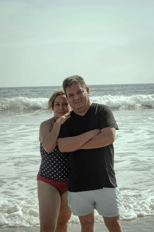 an older couple posing for the camera on the beach