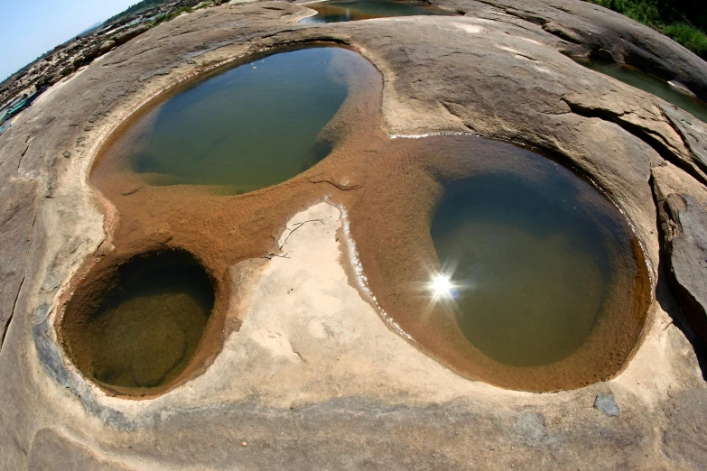 a rocky outcropping with a rock formation surrounding a pool of water