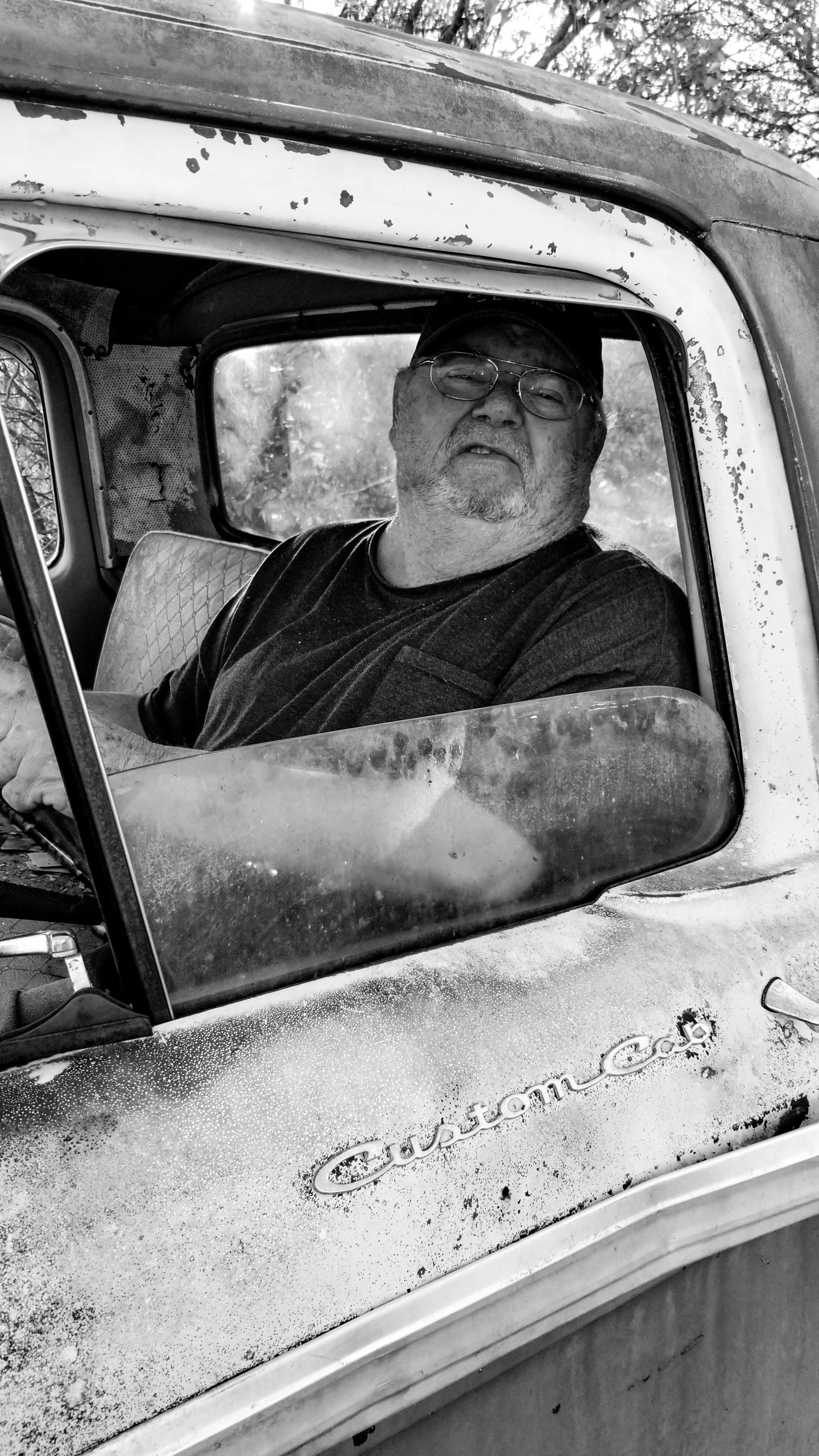 man sitting in the side window of an old pick - up truck