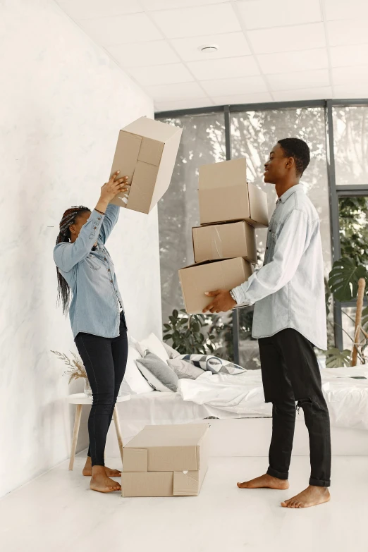 two people carrying cardboard boxes in an office