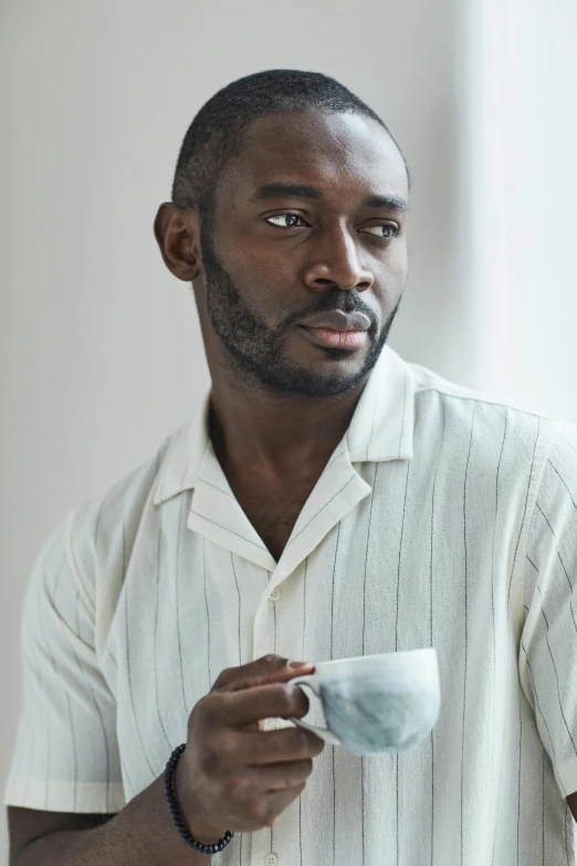 a man wearing a white shirt holding a cup in his left hand