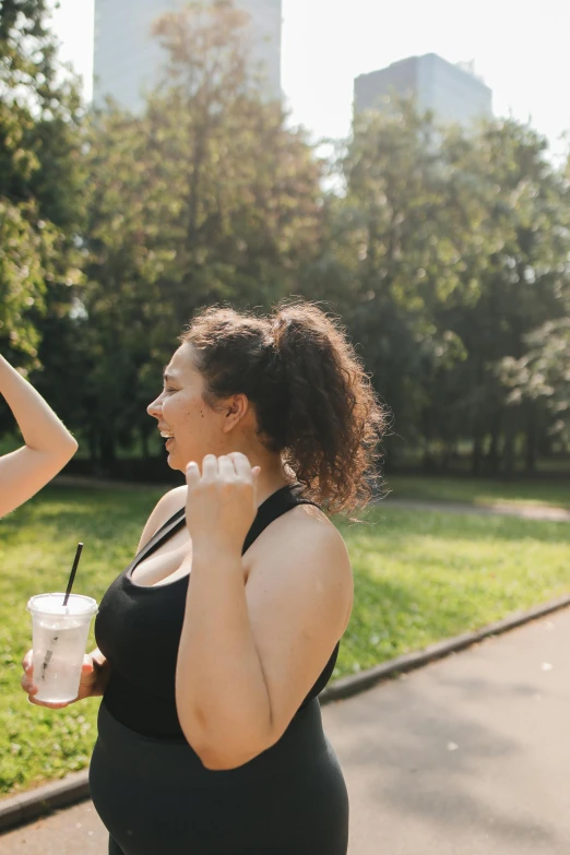 a fat woman in a black dress holds up a drink