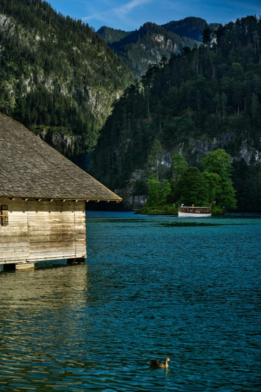 a boat docked by the shore in front of a mountain hut