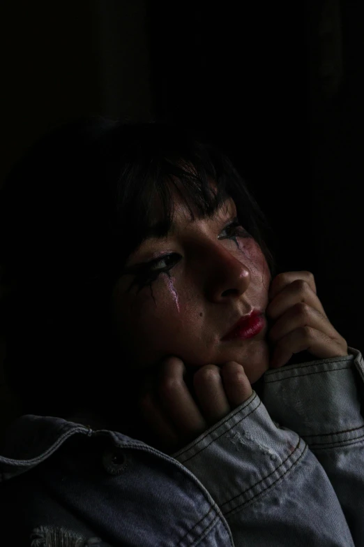 woman in dark room holding her head to her face