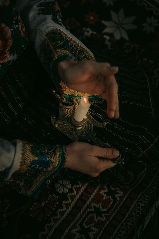 a person's hand holding a candle in their left hand