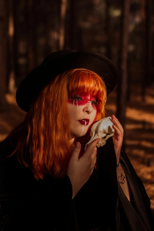 a young lady with orange hair and makeup in a forest