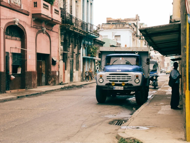 an old, blue truck parked on the side of the road with people on it